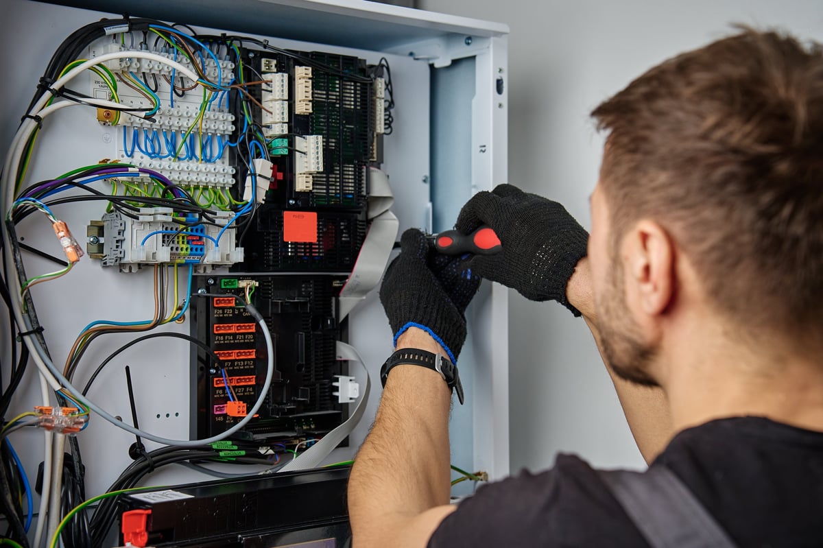 Technician working on internal wiring of heat pump, inspecting electrical connections