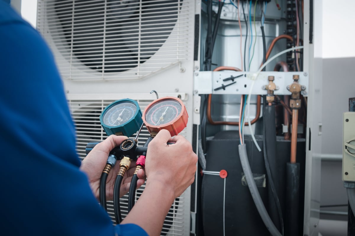 Technician checking air conditioner, measuring equipment for filling air conditioners